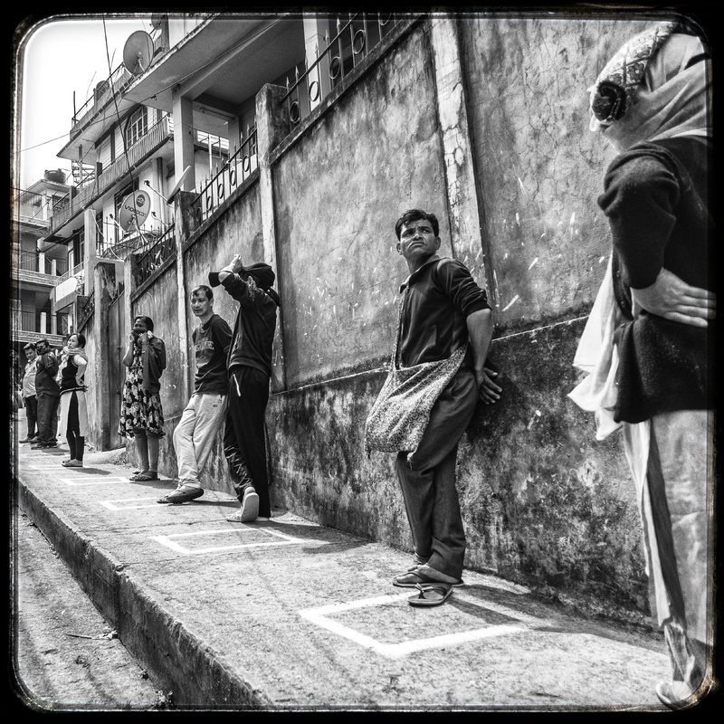 A queue of people waiting outside of a store. 