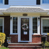 A house has a spring wreath hanging on the front door, along with a drawing of a rainbow.