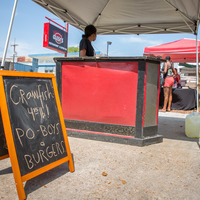 Food tent with a sign that says "Crawfish 4.75lb! Po Boys and burgers."