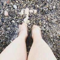 This is a picture taken of a person burying their feet in the small rocks at the bottom of a stream.  