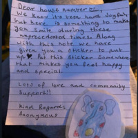 Picture of a letter left with an elephant sticker at someone's doorstep. The letter states that the writer knows times have been hard lately, so hopefully the sticker included might brighten the recipients day when they see it. A form of community support. 