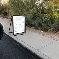 A whiteboard sign on the sidewalk.