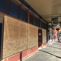 A store with wood over the windows. Hanging from the awning is a sign with a moon on it that says: Blue Nile. 