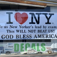 A white sign with black lettering on a glass window. 