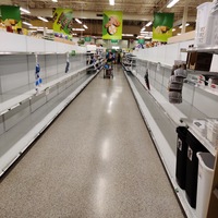 An aisle in a grocery store that has nothing on the shelves. 