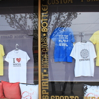 A shop window with various Covid-19 themed t-shirts on display. 