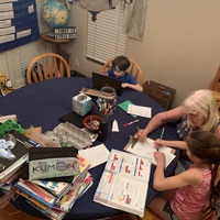 Two children doing homework with an older woman. 