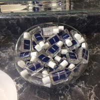 A glass bowl full of travel size hand sanitizer bottles. 