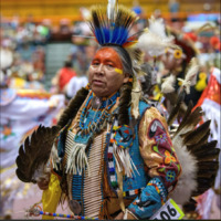 This is a picture of a Native American man dressed in traditional ceremonial clothing, likely at a powwow. 