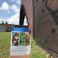 A sign that is stuck into the ground that says: Crescent City Farmers Market temporarily closed. 