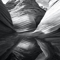 This is a black and white photo of the image of a canyon reflecting from a pool of water at its bottom. 