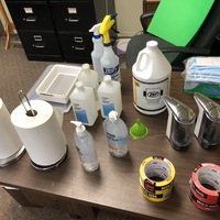 A table covered in various cleaning supplies in preparation for reopening.