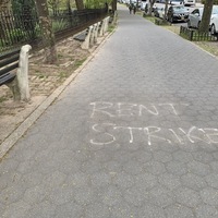 white spray paint on the sidewalk saying "rent strike" 