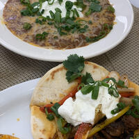 This is a picture of a bowl of soup and what seems to be a taco that is sitting on a table ready to eat. 