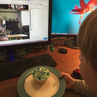 A child having a cupcake to celebrate a birthday party via zoom. 