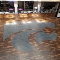 This is a picture taken of a logo inlaid into a wooden floor. 