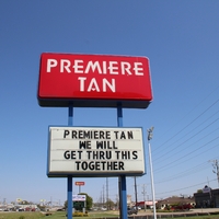 A business sign reading "Premiere Tan, We Will Get Thru This Together". 