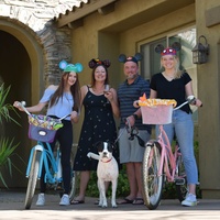 Four people posing for a picture, two with bikes and one holding a dog. 