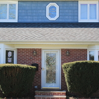 Rainbow drawings and paintings are on the front windows of the house. The front of the house has a spring wreath on the front door. 