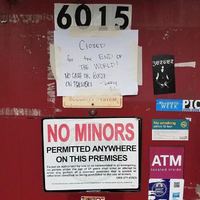 Red door with multiple signs. One signed taped with text, "CLOSED for the END OF THE WORLD! NO CASH OR BOOZE ON PREMISES - SORRY LL" and sign below "NO MINORS PERMITTED ANYWHERE ON THIS PREMISES"