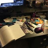 This is a picture of a desk covered in notebooks, pens, and pencils. 