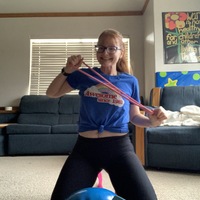 Photo of a woman smiling and stretching out an exercise band.