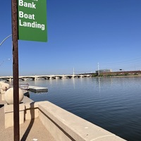 This is a picture of a face mask that has been discard by a boat dock. A bridge can be seen in the background. 