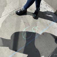 A sidewalk has measurements drawn on it with chalk to indicate 6 feet of distance for social distancing. 