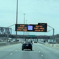 Image of a sign on the highway in both English and French which says stop Covid-19, stay home.