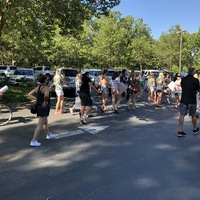 This is a picture taken of a group of people holding signs and protesting while walking down a street. Many are wearing face masks. 