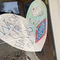 A paper heart that is taped to the inside of a front door that says: Wash UR HANDS PLS