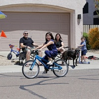 A girl riding a bike in front of a family. 