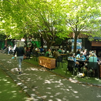 A picture of people sitting at tables outside at a restaurant. 