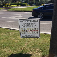 A sign in a grass patch next to a road. 