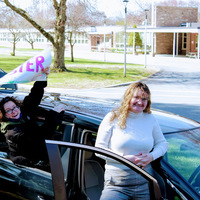 Two women in front of a black vehicle. 