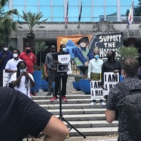 Image of people gathered, wearing masks, in front of city hall in New Orleans for the Solidarity Conference.