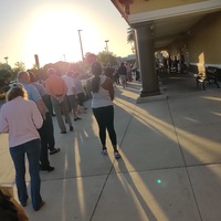 A long line of people are waiting outside of a grocery store. 