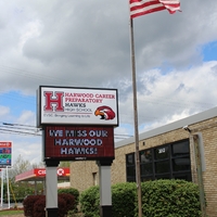 A sign outside a school reading "we will miss our Harwood Hawks".