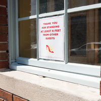 A white sign with red letters in a window.