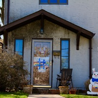 The front of a house has rainbow drawings and a blue hashtag on the front door. 