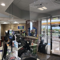 A photo of a checkout counter in a store with a plexiglass divider between the customer side and the cashier side.