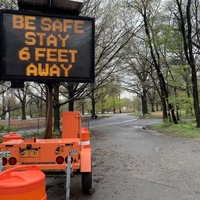 an orange neon sign telling people to stay 6 feet apart