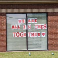 Signs in a window reading "We are all in this together".