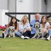 A family photo of four people and two dogs. 