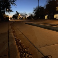 This is a picture taken of a discarded cloth face mask resting on a city street as the sun sets in the background. 