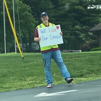 A man holding a sign reading "We Love Our Grads".