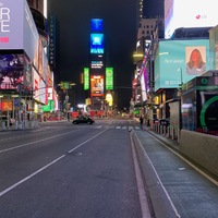 This is a picture taken of a mostly empty street, with many brightly colored electronic billboards in the background. 