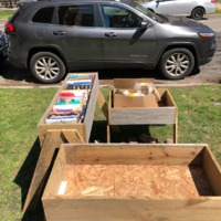 wood boxes with books in them on the side of the road