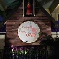 House decorated for Mardi Gras.  A white cardboard clock has a pink flamingo in the center and text which reads, "Cuckoo From Covid". 