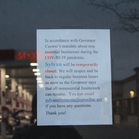 A window sign that say "In accordance with Governor Cuomo's mandate about nonessential businesses during the COV-ID19 pandemic, Sylvan will be temporarily closed. We will reopen and be back to regular business hours as soon as the Governor says that all nonessential businesses can resume. you can e-mail sylvanofmineola@optonline.net if you have any questions. Thank you!" 